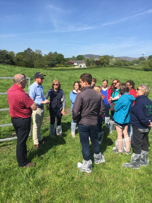 Group in a field with the farmer, having a discussion. Standing beside a gate, in a field of grass and with blue sky